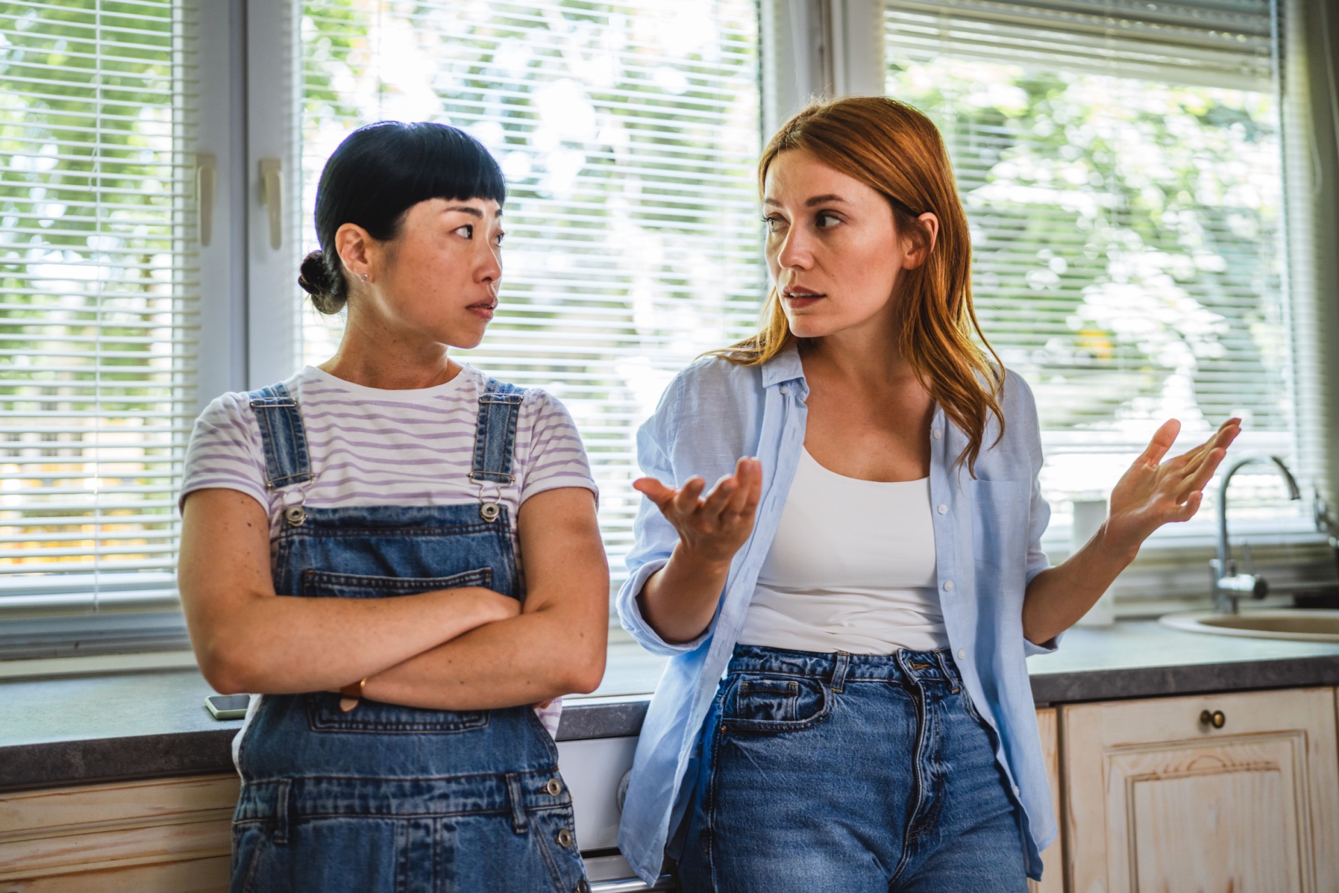 Et lesbisk par eller to venninner står og diskuterer på et kjøkken, misforståelser og problematisk relasjon