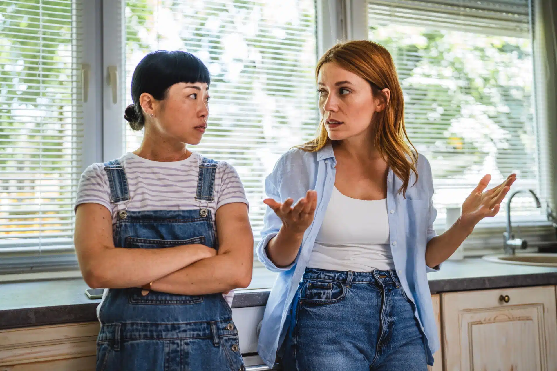 Et lesbisk par eller to venninner står og diskuterer på et kjøkken, misforståelser og problematisk relasjon